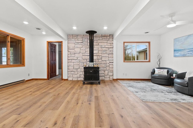 unfurnished living room with visible vents, wood finished floors, a wood stove, and baseboards