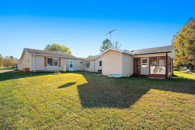 rear view of house featuring a sunroom and a lawn