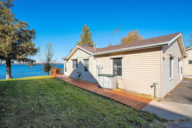 rear view of property with a deck with water view and a yard