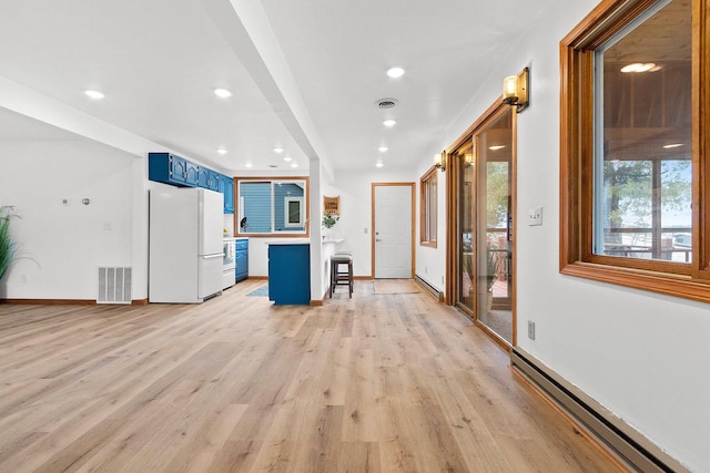 kitchen featuring visible vents, a baseboard radiator, light wood-style flooring, freestanding refrigerator, and blue cabinets