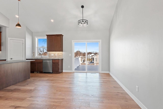 kitchen with light wood-style floors, a wealth of natural light, stainless steel dishwasher, and tasteful backsplash