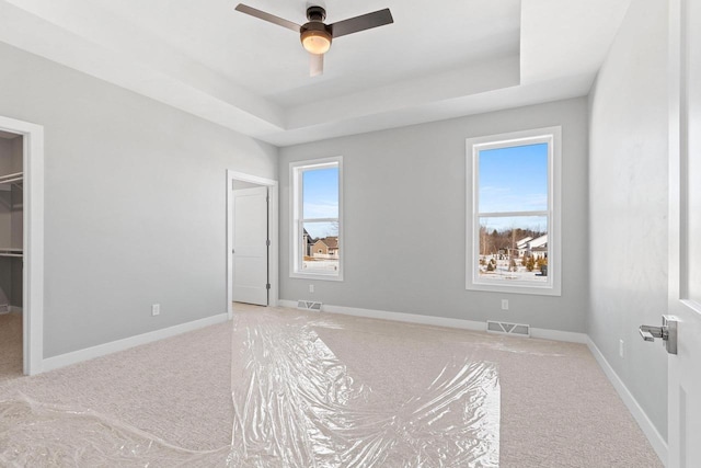 bedroom with multiple windows, visible vents, and a raised ceiling