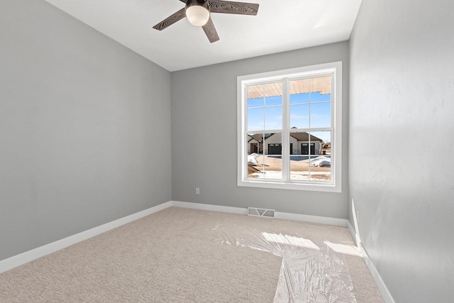 empty room featuring baseboards, visible vents, ceiling fan, and light colored carpet