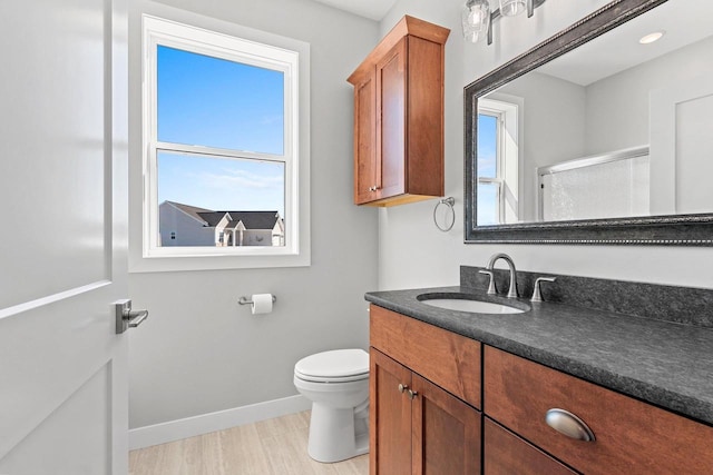 full bathroom featuring toilet, wood finished floors, vanity, baseboards, and a shower with door