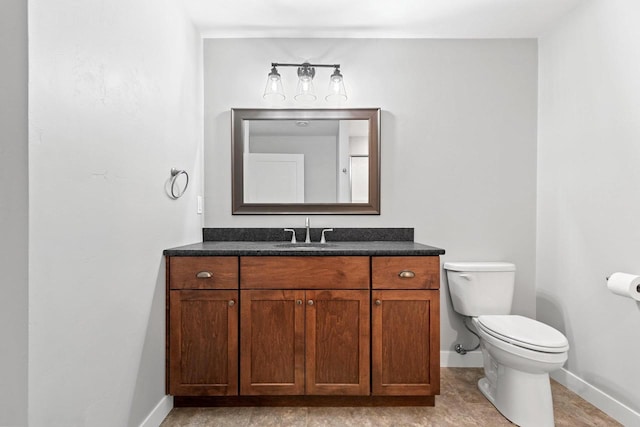 bathroom featuring baseboards, vanity, and toilet