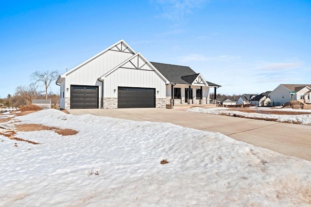 modern inspired farmhouse featuring an attached garage, covered porch, stone siding, driveway, and board and batten siding