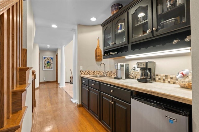 bar with dishwashing machine, light wood-type flooring, ornate columns, a sink, and recessed lighting