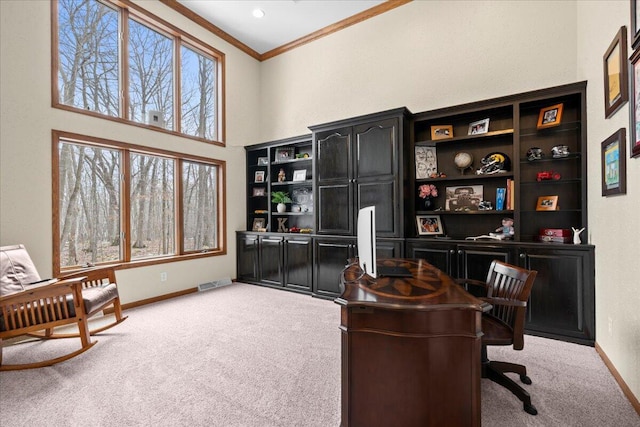 carpeted office featuring ornamental molding, a high ceiling, visible vents, and baseboards