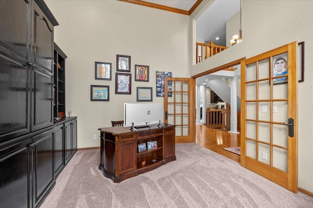 office space featuring baseboards, light colored carpet, a high ceiling, crown molding, and french doors