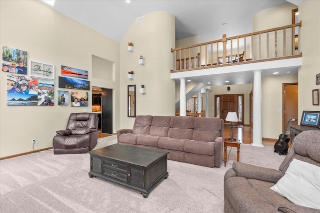 carpeted living area with a towering ceiling, baseboards, stairs, visible vents, and ornate columns