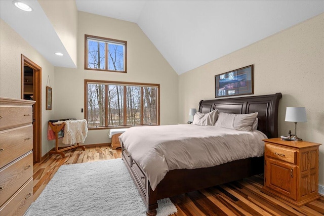 bedroom with light wood-style flooring, high vaulted ceiling, and baseboards