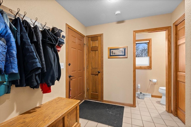 mudroom featuring a textured ceiling, baseboards, and light tile patterned floors