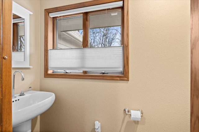 bathroom featuring a textured wall and a sink