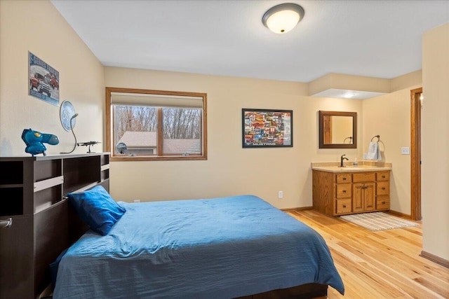 bedroom with baseboards, a sink, and light wood finished floors