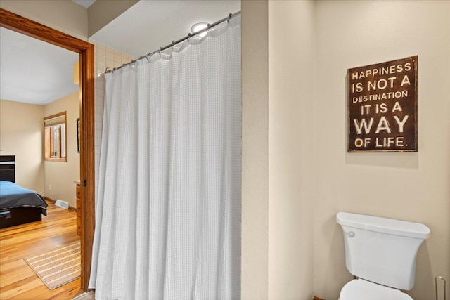 bathroom featuring connected bathroom, toilet, a shower with shower curtain, wood finished floors, and baseboards