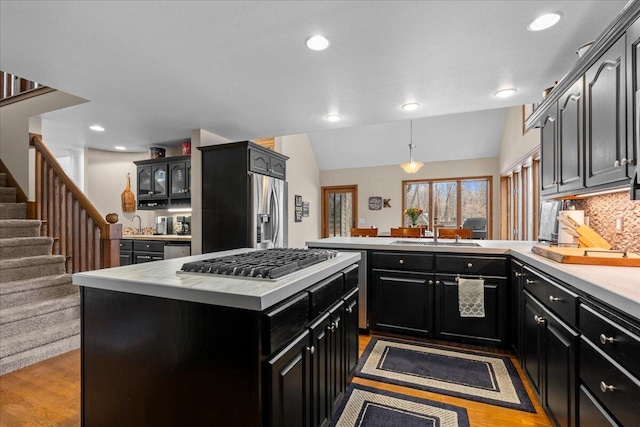 kitchen featuring stainless steel appliances, light countertops, dark cabinets, and a peninsula