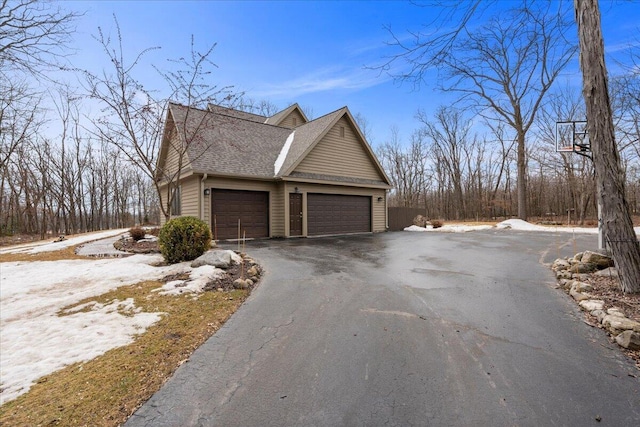 snow covered property featuring roof with shingles and driveway