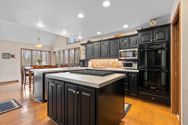 kitchen with a center island, stainless steel appliances, light countertops, a sink, and a peninsula