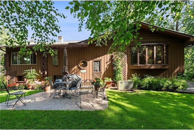 115 Pine Crest Rd, Balsam Lake, WI 54810 - back of house with a patio area, a chimney, board and batten siding, and a yard