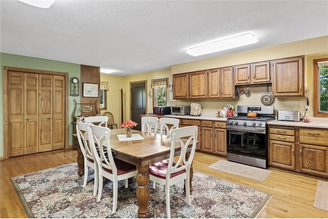 115 Pine Crest Rd, Balsam Lake, WI 54810 - kitchen featuring stainless steel range with gas cooktop, brown cabinets, light countertops, light wood-style floors, and a textured ceiling