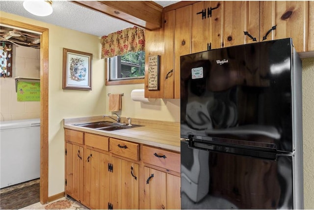 115 Pine Crest Rd, Balsam Lake, WI 54810 - kitchen with brown cabinets, light countertops, freestanding refrigerator, a sink, and a textured ceiling
