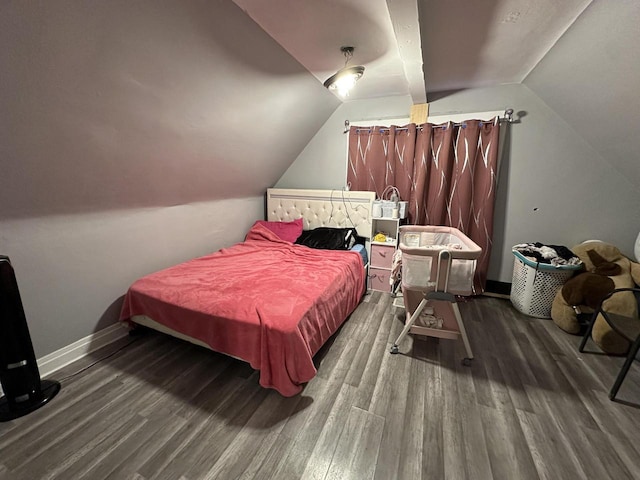 bedroom with vaulted ceiling, wood finished floors, and baseboards