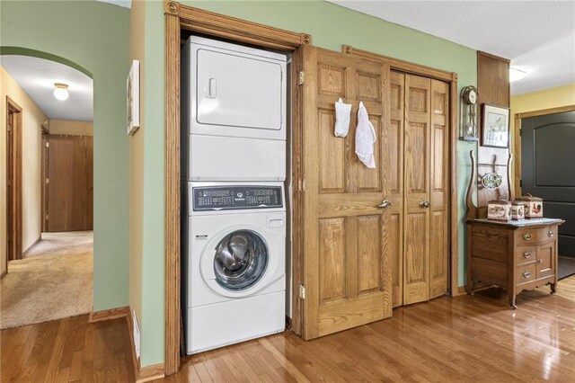 115 Pine Crest Rd, Balsam Lake, WI 54810 - laundry area featuring laundry area, baseboards, arched walkways, stacked washer / dryer, and wood finished floors