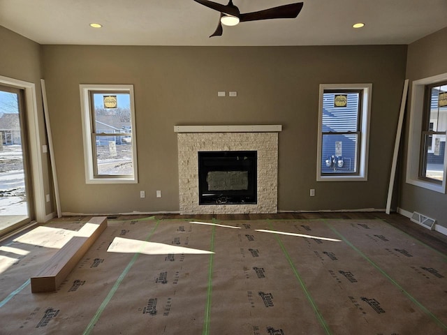 unfurnished living room with a healthy amount of sunlight, a fireplace, baseboards, and recessed lighting