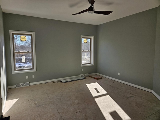 empty room with a ceiling fan, plenty of natural light, visible vents, and baseboards