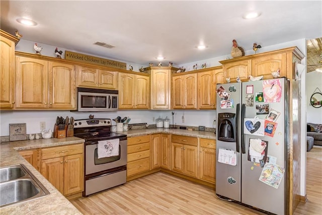 kitchen with visible vents, appliances with stainless steel finishes, light countertops, light wood-style floors, and a sink