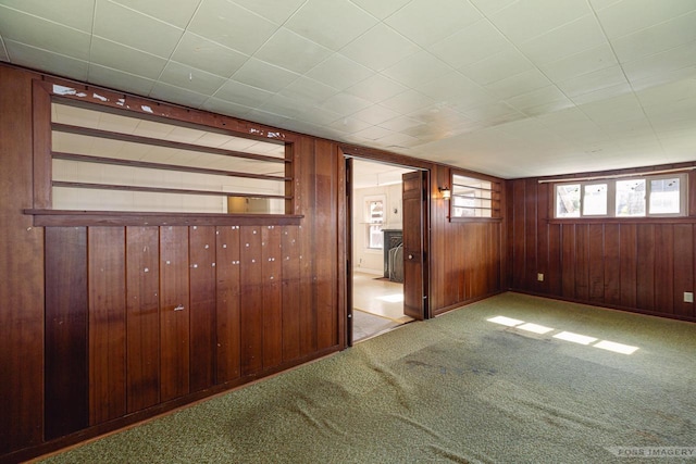 unfurnished room featuring wood walls and carpet