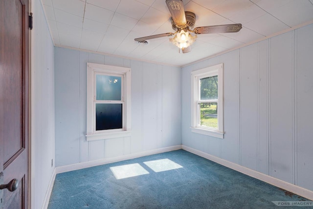 empty room with carpet flooring, a ceiling fan, and baseboards