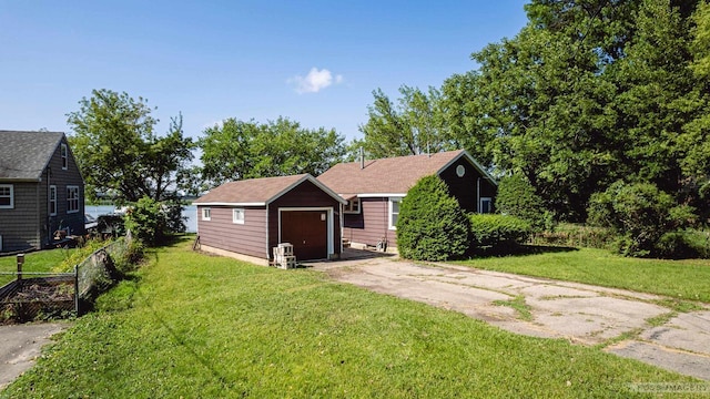 bungalow featuring concrete driveway, an outdoor structure, and a front lawn