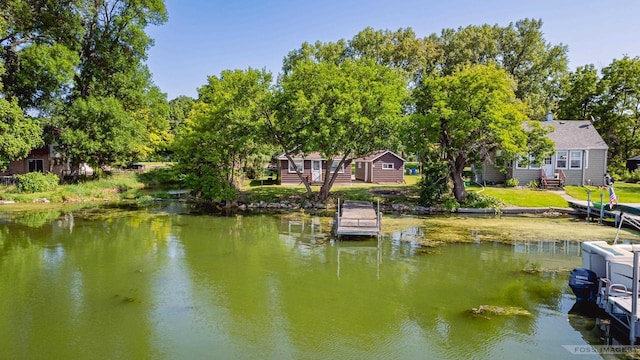 dock area with entry steps, a water view, and a lawn