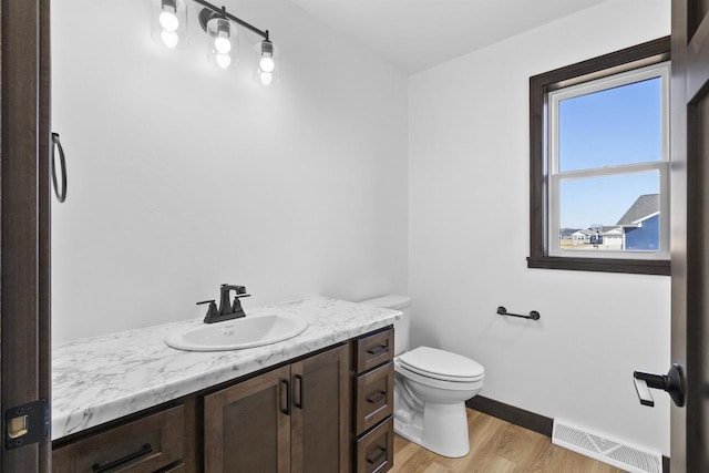 3752 Westpoint Rd, Suamico, WI 54313 - half bathroom featuring toilet, wood finished floors, vanity, visible vents, and baseboards