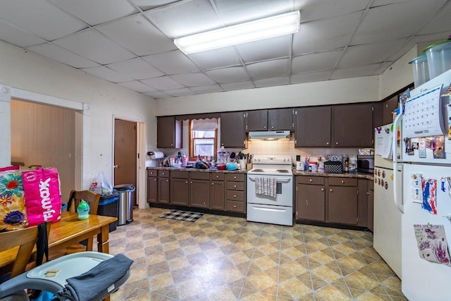 kitchen with white appliances, a drop ceiling, backsplash, under cabinet range hood, and a sink