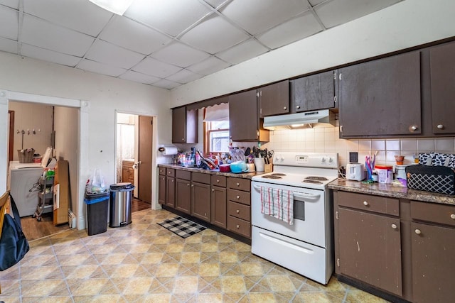 kitchen featuring dark brown cabinetry, a paneled ceiling, under cabinet range hood, white electric range, and decorative backsplash