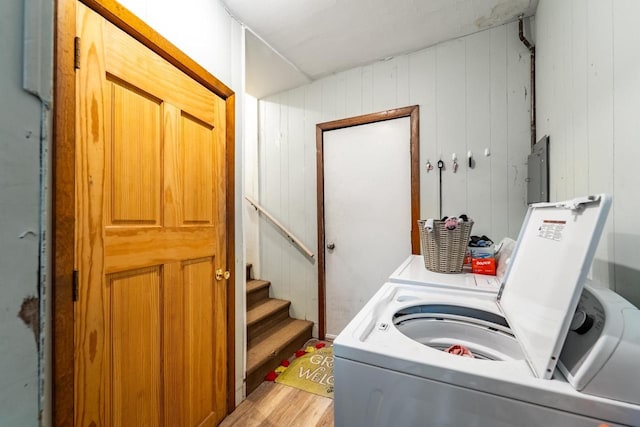 clothes washing area with light wood-style floors, laundry area, electric panel, and washer and clothes dryer