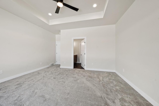 unfurnished bedroom featuring carpet, recessed lighting, a raised ceiling, ensuite bath, and baseboards