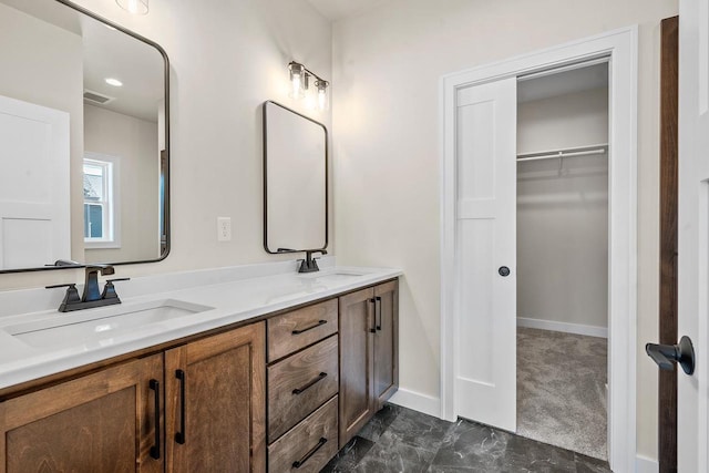 bathroom with double vanity, baseboards, visible vents, and a sink