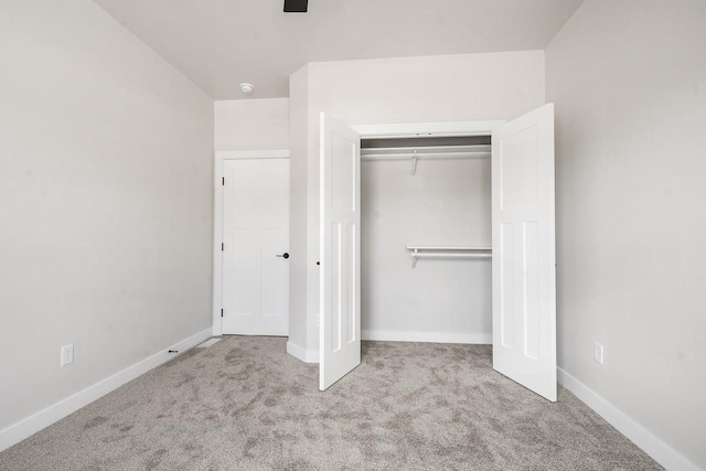 unfurnished bedroom with a closet, carpet, and baseboards