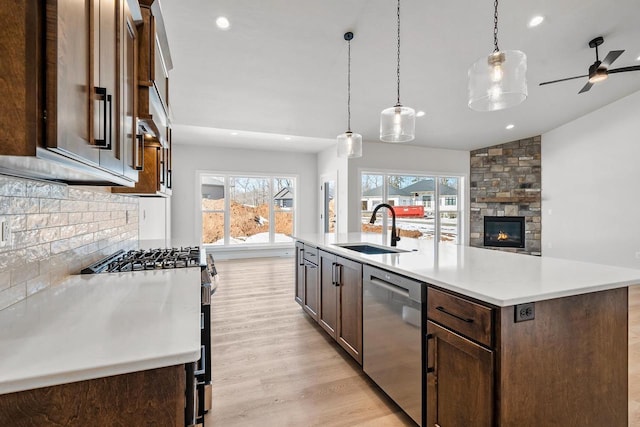 kitchen with stainless steel appliances, light countertops, light wood-style floors, open floor plan, and a sink