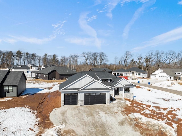 view of front of house with a residential view, stone siding, driveway, and an attached garage