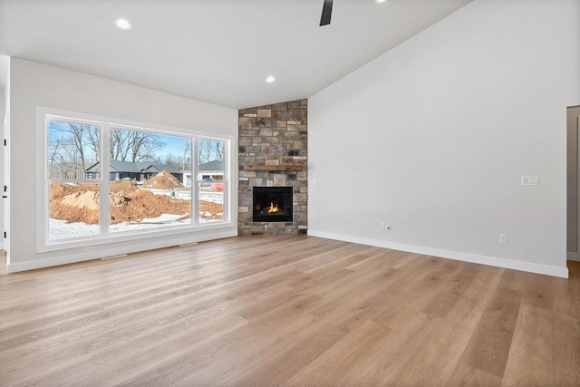 unfurnished living room with recessed lighting, a stone fireplace, light wood-style flooring, and baseboards