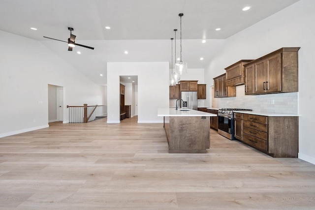 kitchen featuring a center island with sink, high vaulted ceiling, stainless steel appliances, and open floor plan