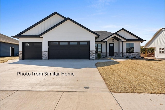 modern farmhouse style home with concrete driveway, stone siding, board and batten siding, and an attached garage