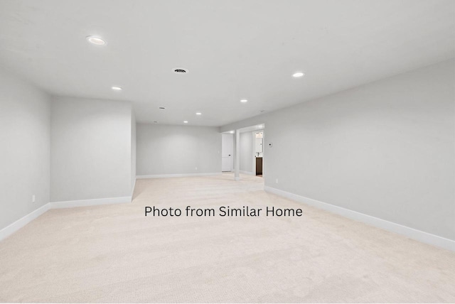 spare room featuring light carpet, baseboards, and recessed lighting