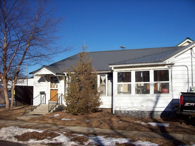 view of front of house featuring metal roof and fence