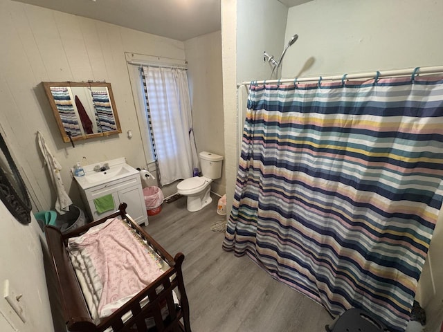 full bath featuring toilet, a shower with curtain, a sink, and wood finished floors