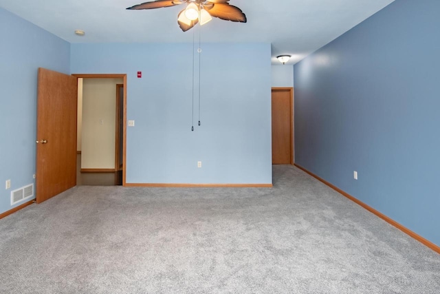 carpeted empty room featuring a ceiling fan, visible vents, and baseboards